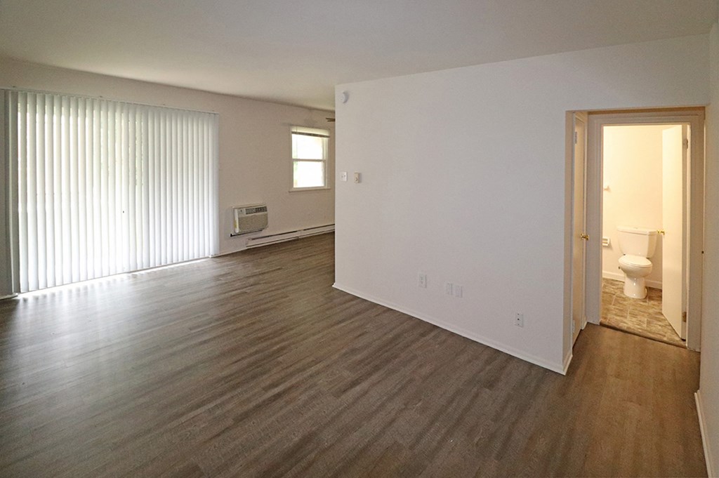 an empty living room with a white wall and wood flooring