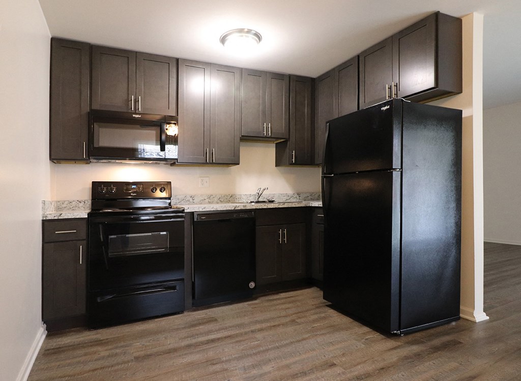 a kitchen with black appliances and dark wood cabinets