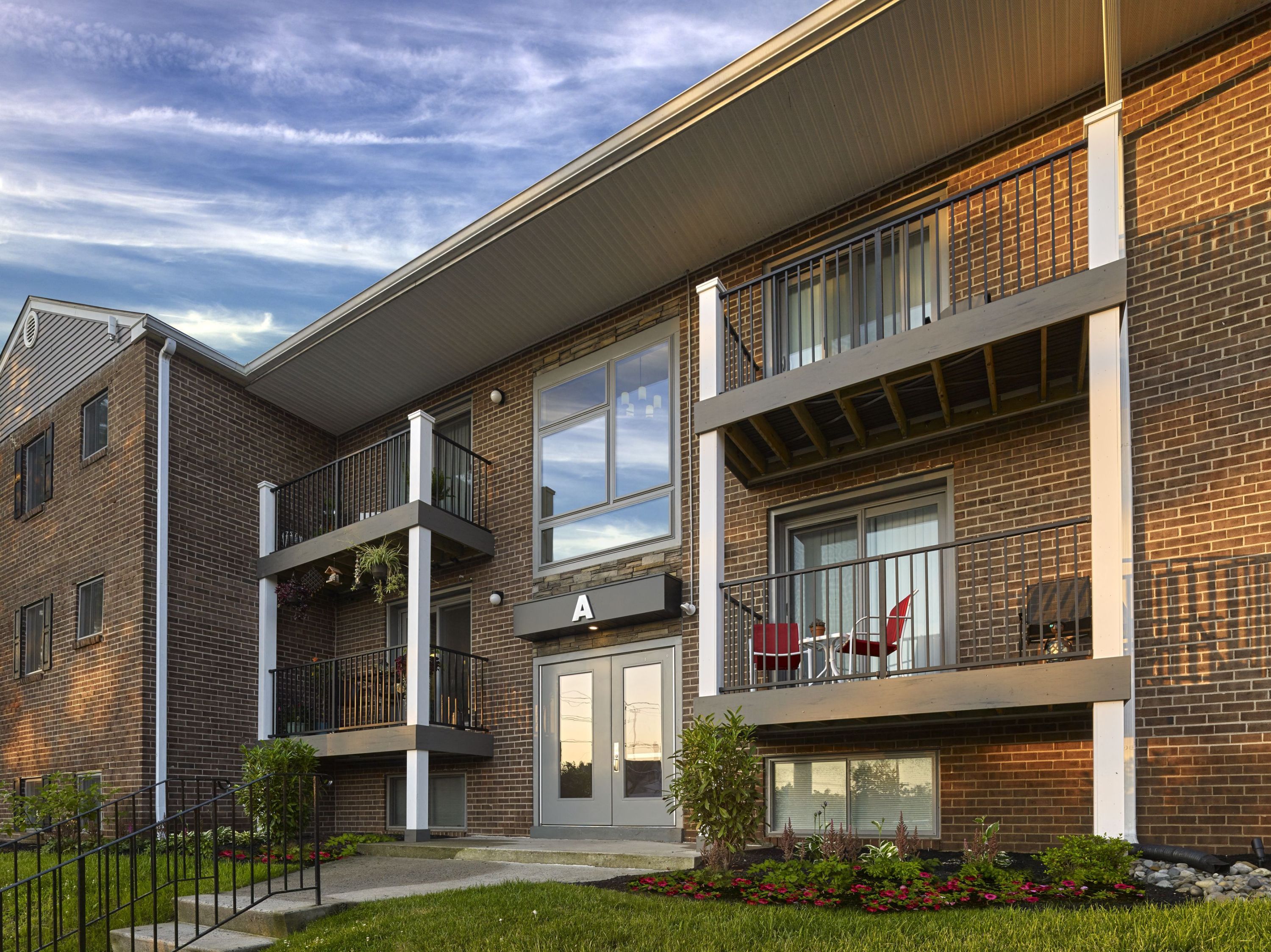a rendering of a brick apartment building with red chairs on the balcony