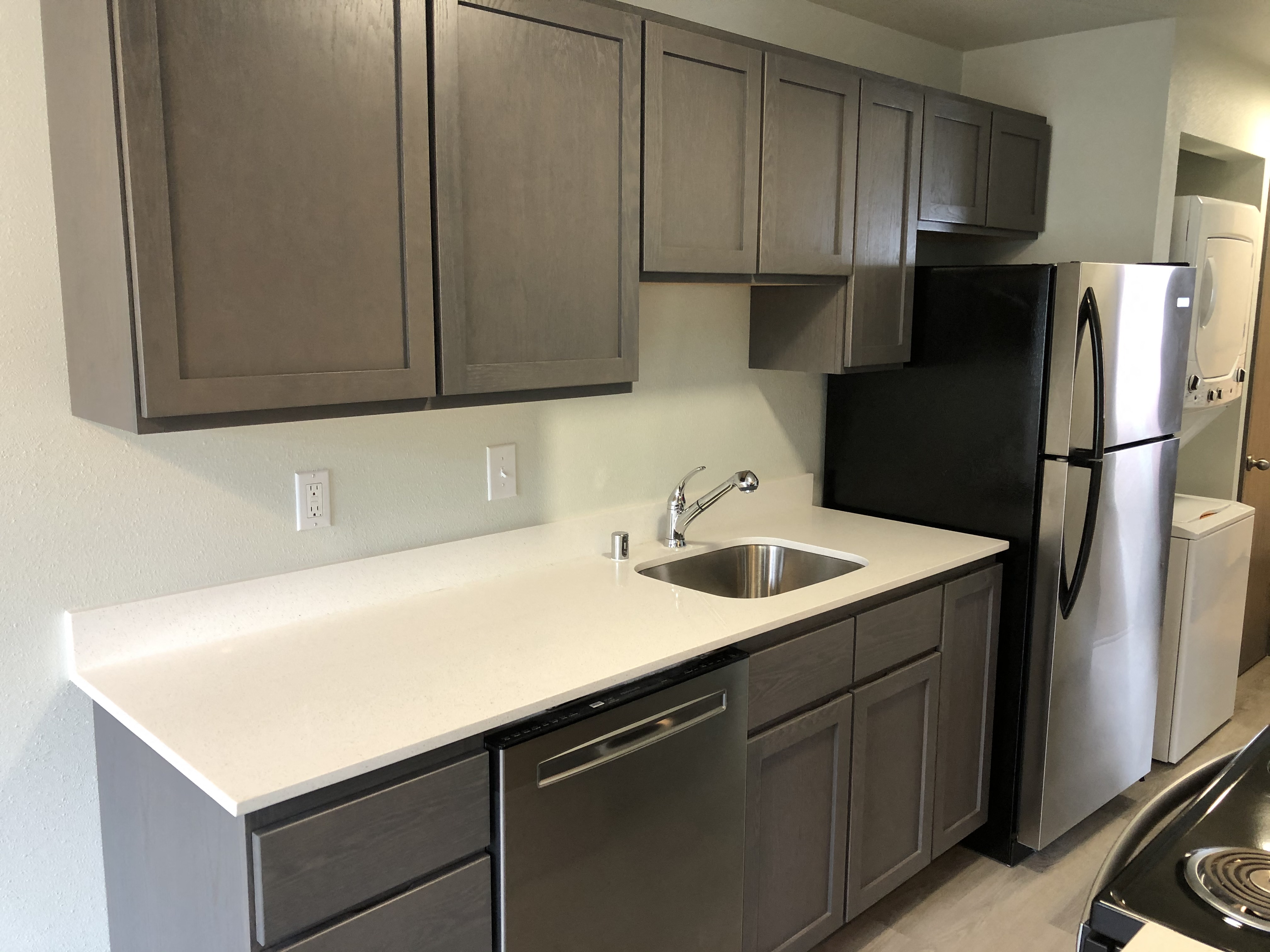 A kitchen with a black refrigerator and stainless steel appliances.
