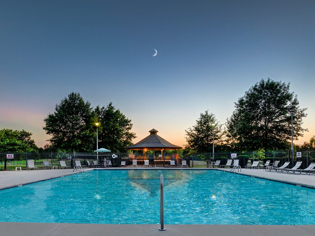 a pool at dusk with a crescent moon in the sky