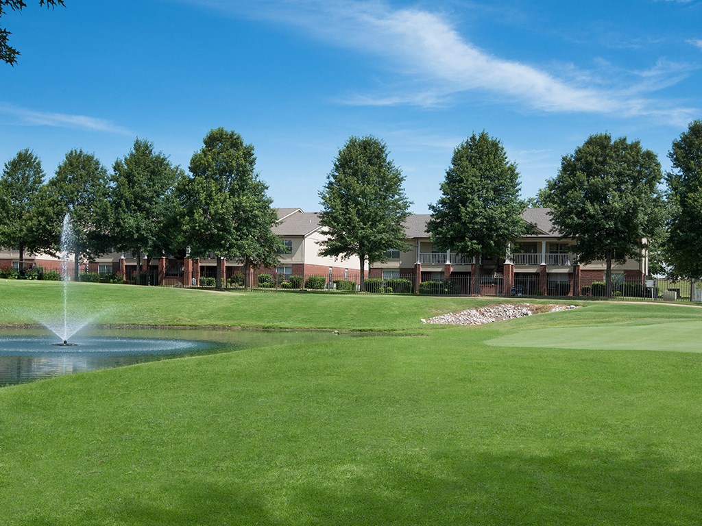 a golf course with a fountain and a building in the background