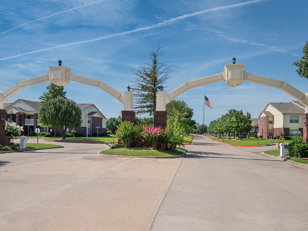 an archway over a street in a neighborhood with a flag and trees