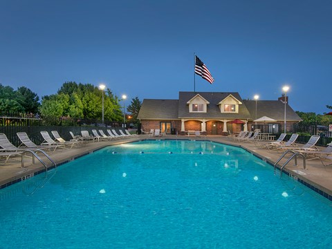 a swimming pool with chairs and an flag at night