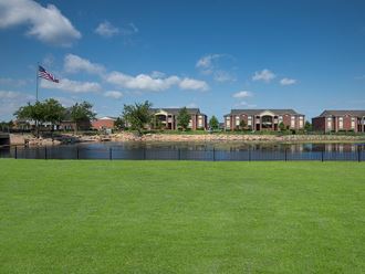 an flag flies over a lush green lawn in front of a pond and