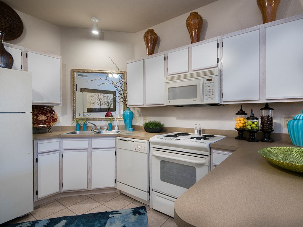 a kitchen with white cabinets and a white stove and microwave