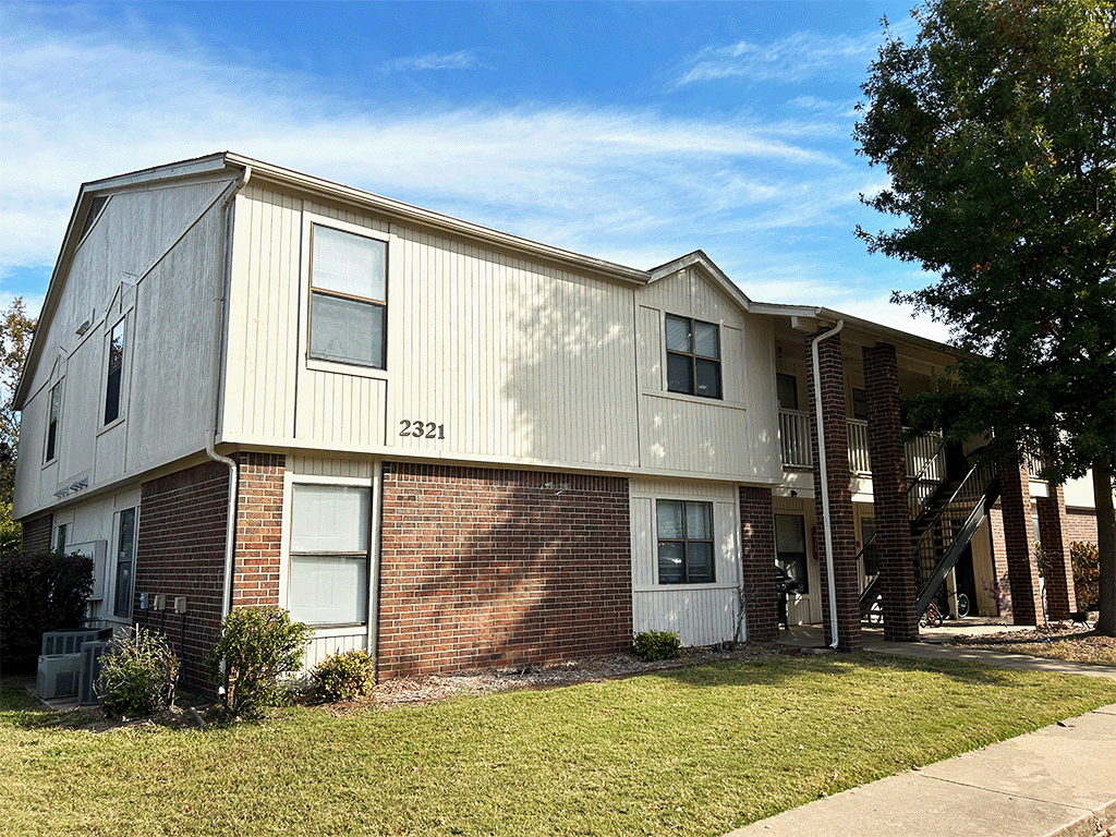 a side view of an apartment building with a lawn