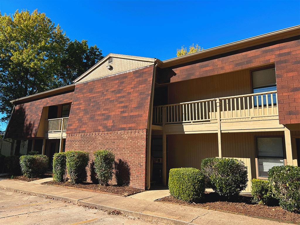 an apartment building with a balcony and a sidewalk