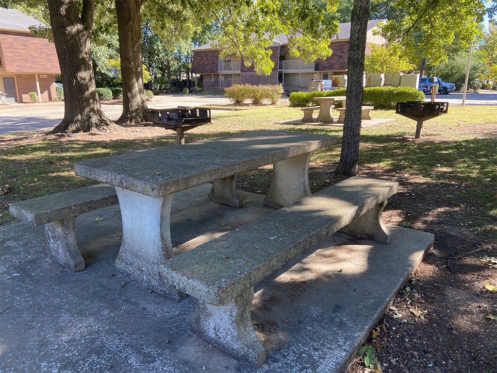 a concrete picnic table and benches in a park