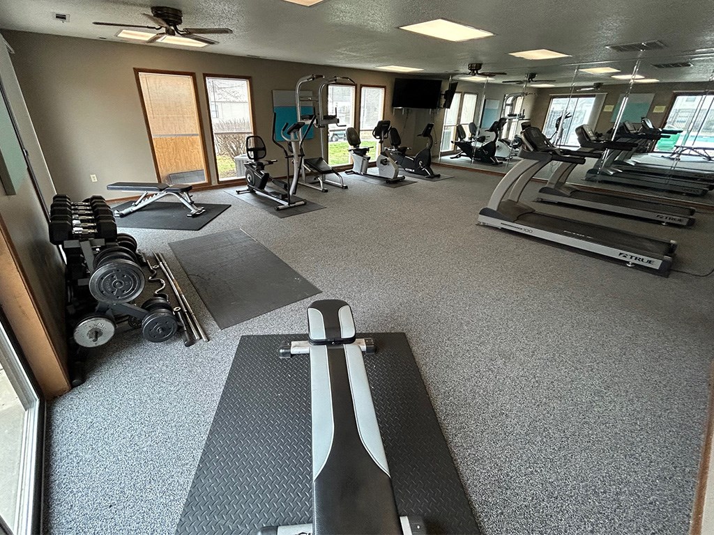 a gym with cardio machines and weights on the floor