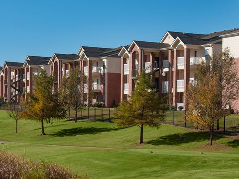 an apartment building with green grass and trees in front of it
