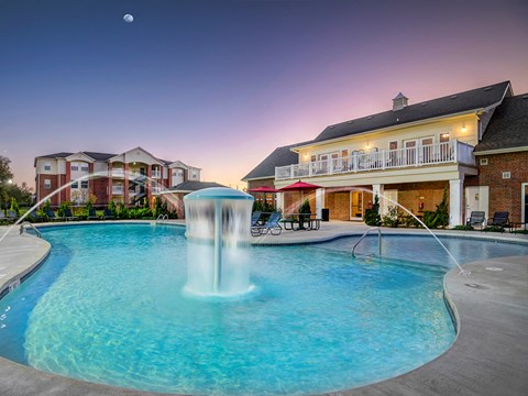 a large swimming pool with a fountain in front of a house