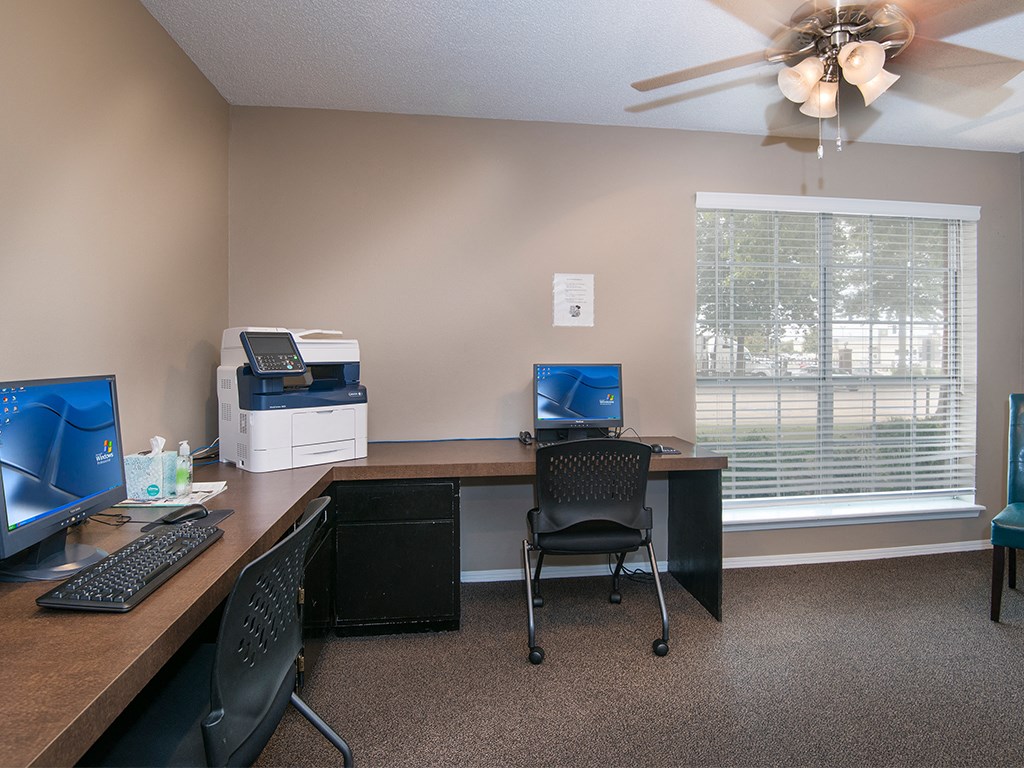 an office with a desk with a computer and a window