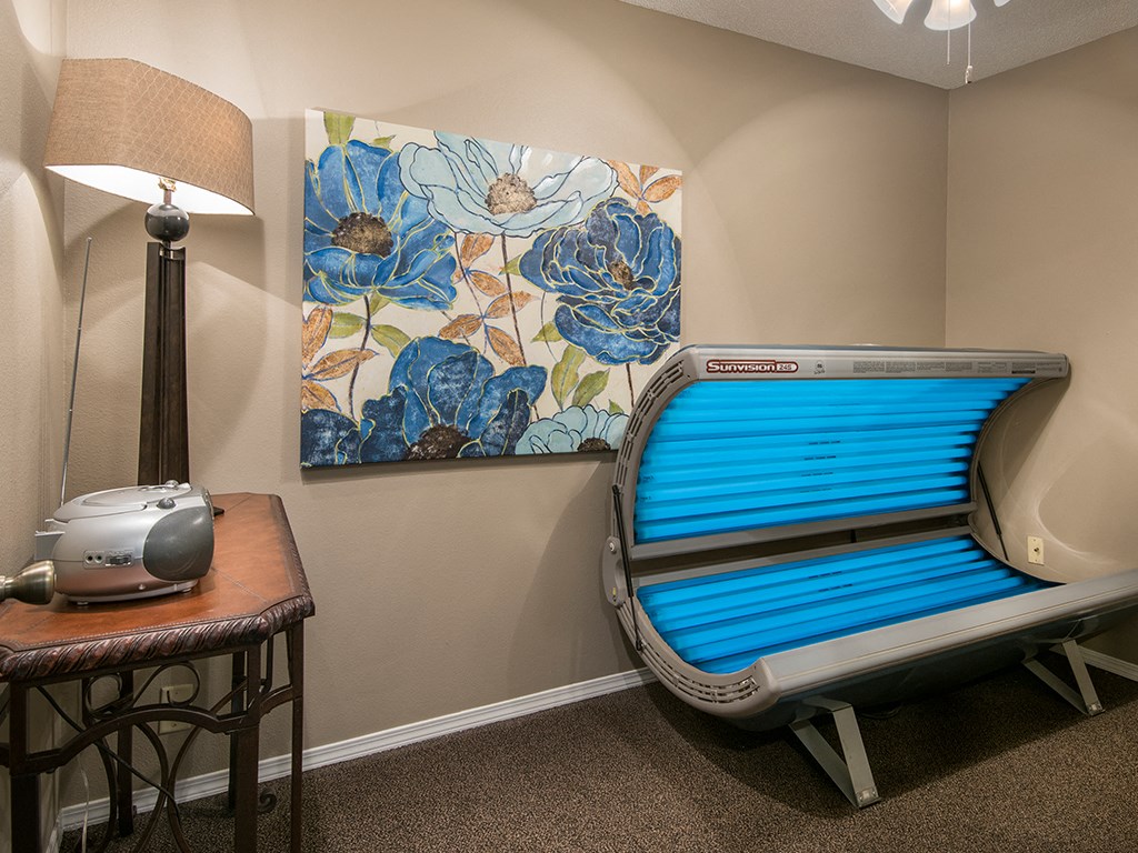 an empty patient room with a blue patient bench and a table with a lamp