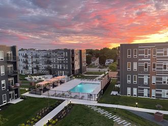 an aerial view of an apartment complex with a pool at sunset