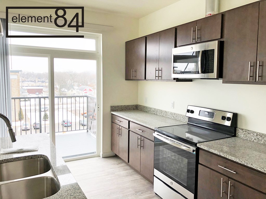 an empty kitchen with stainless steel appliances and a door to a balcony