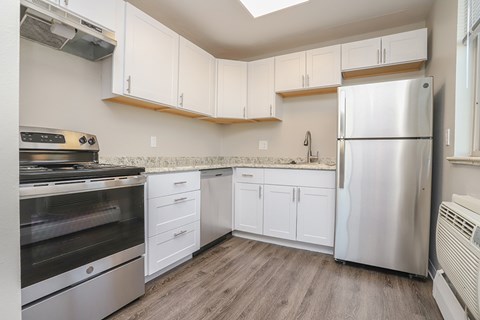 A kitchen with white cabinets and a stainless steel refrigerator.