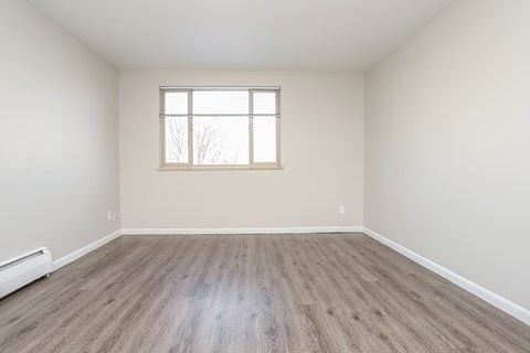A room with a window and wooden flooring.