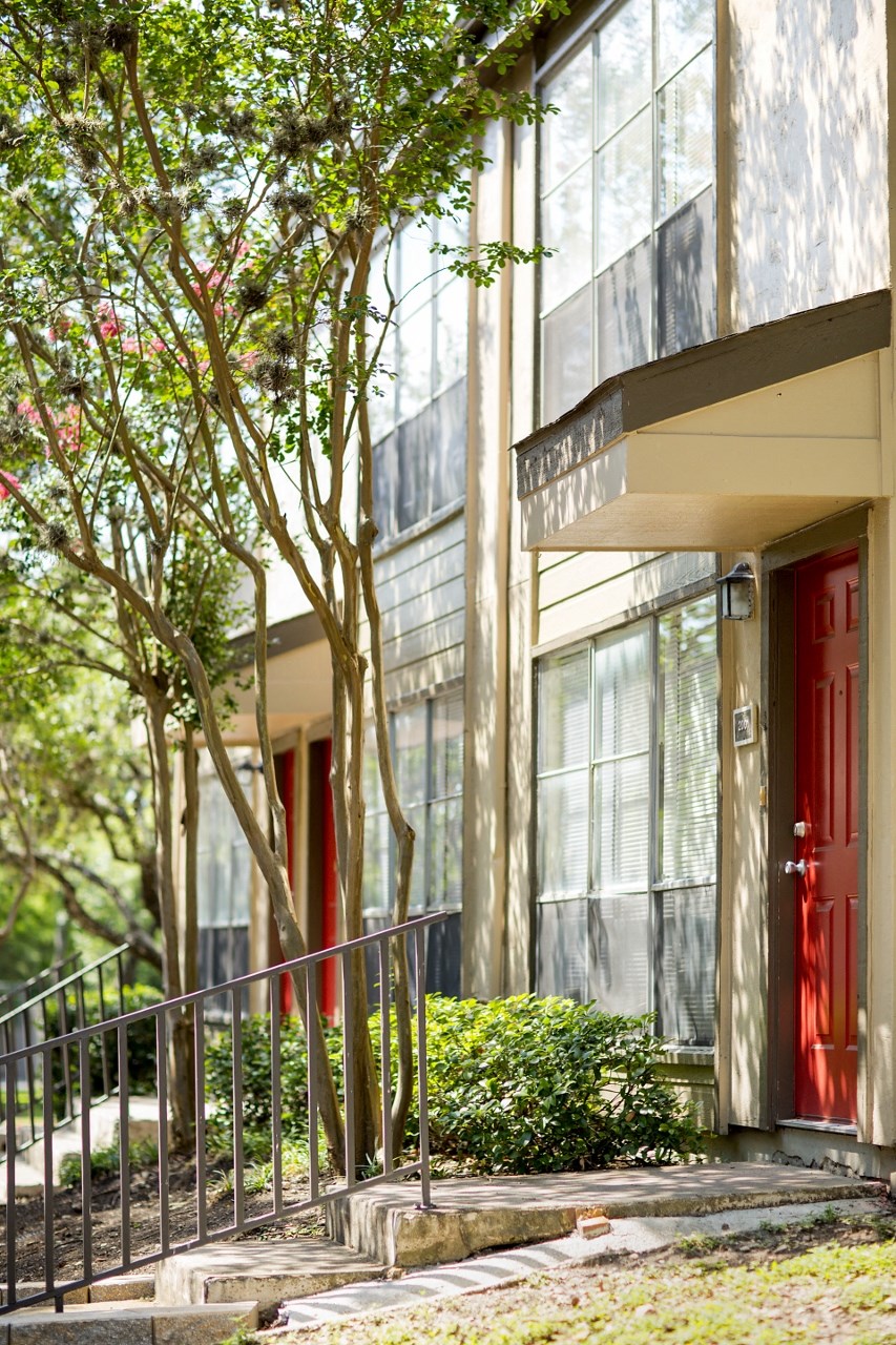 a building with a red door and trees in front of it