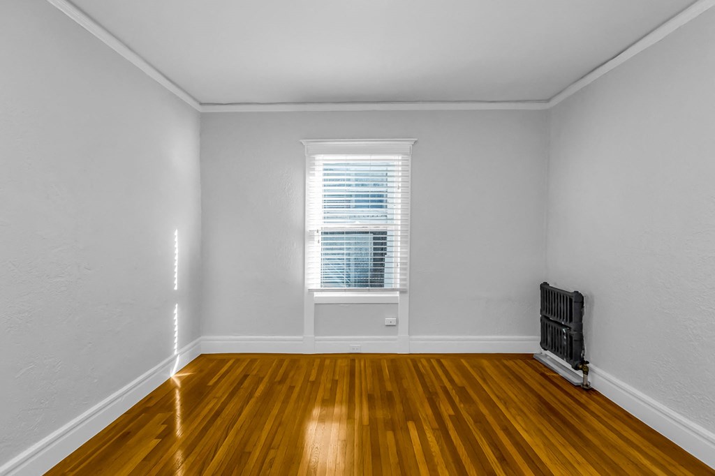 A room with wooden floors and a window with blinds.