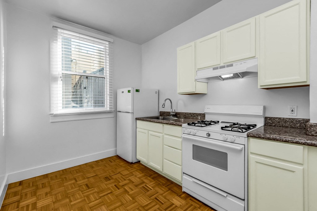 A kitchen with a white stove and white cabinets.