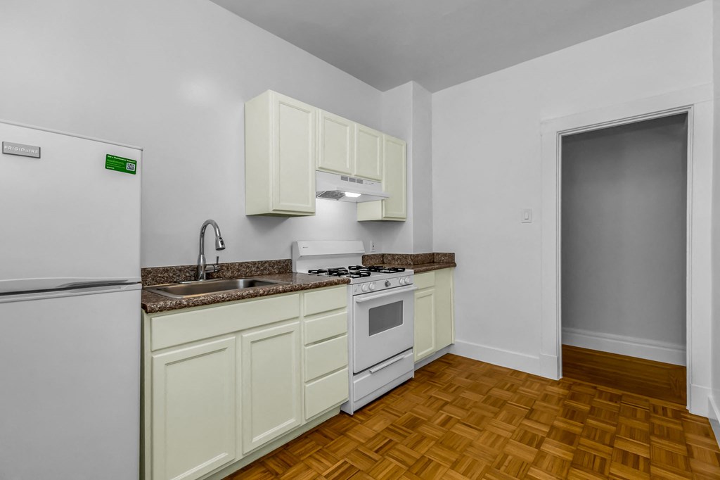A kitchen with white appliances and wooden floors.