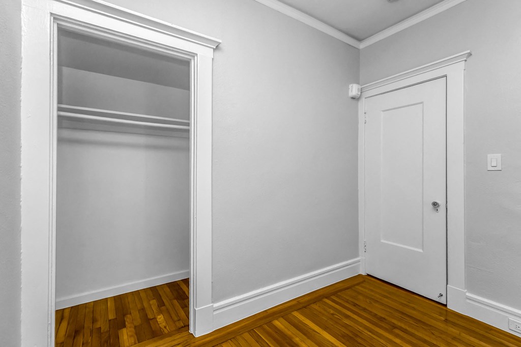 A white door is on the right side of a room with a window on the left.