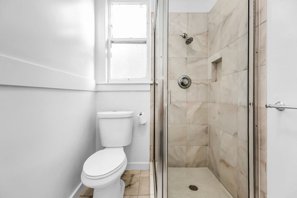 A white toilet sits next to a walk-in shower.