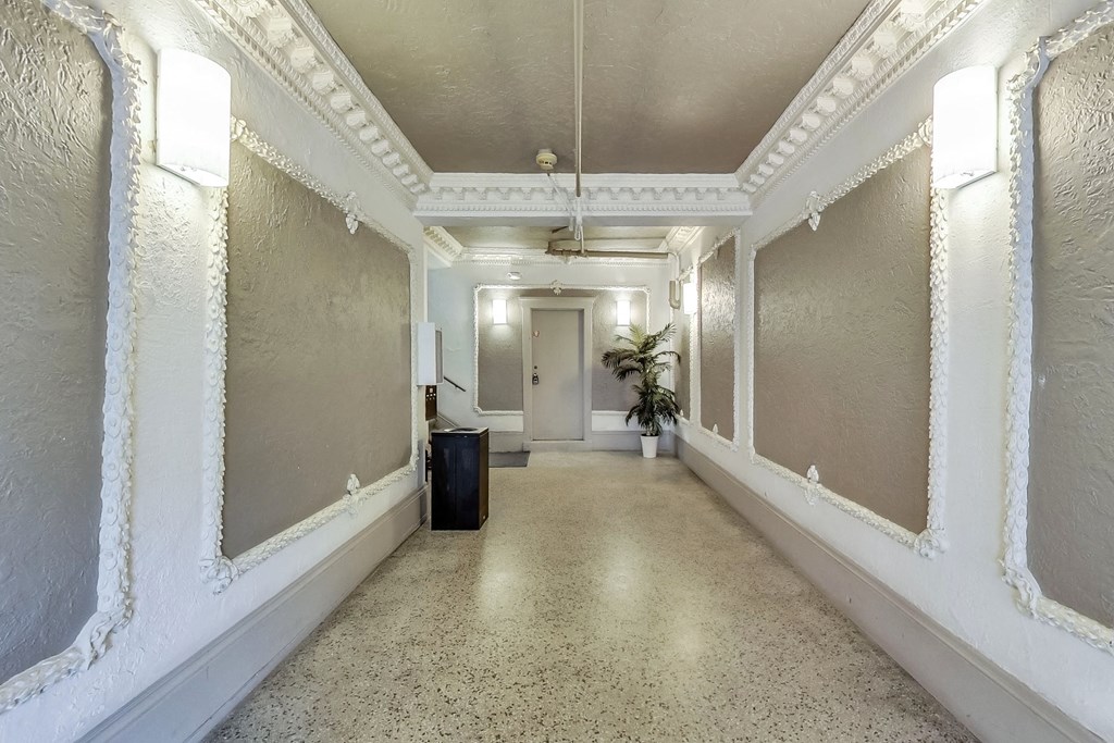 A long hallway with white walls and a trash can.