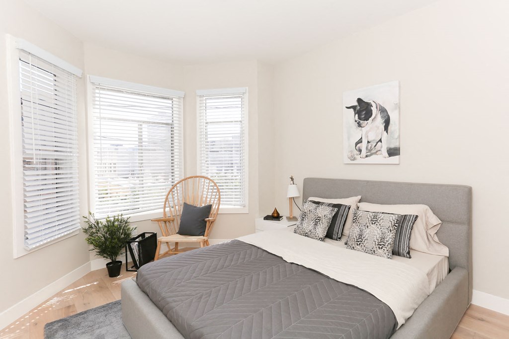 a bedroom with a bed and a chair and a painting of a dog