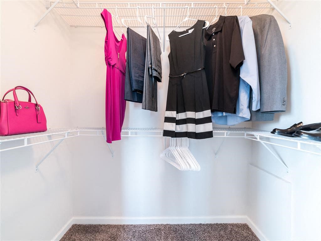 a closet with a rack of clothes and a pink purse