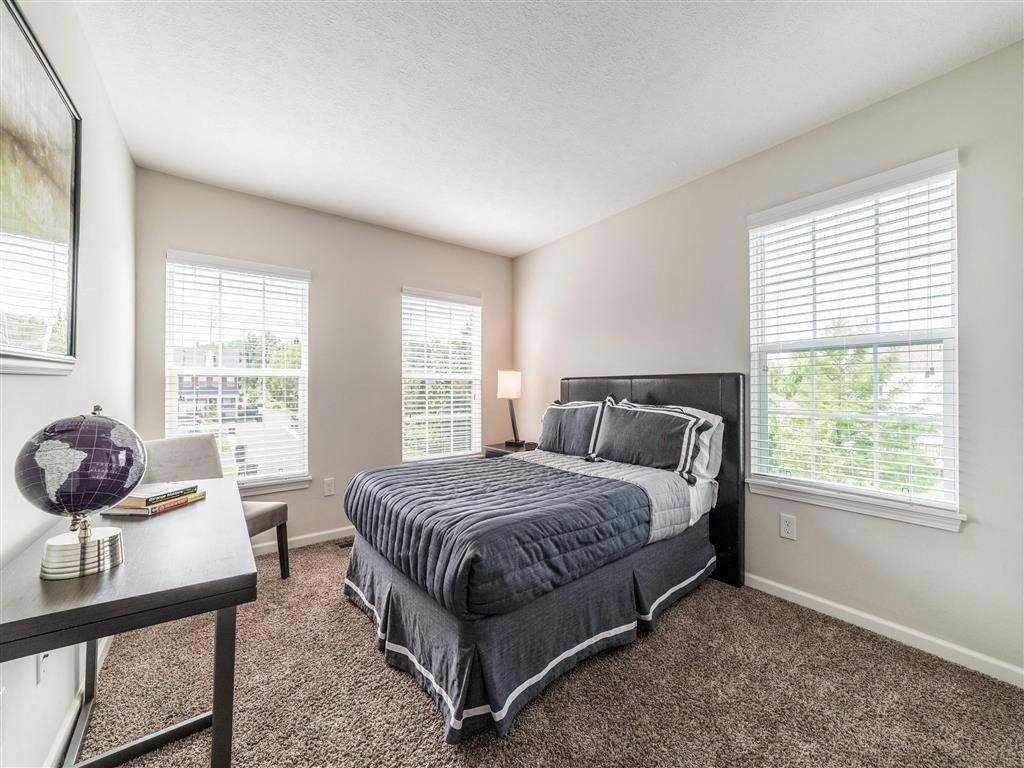 a bedroom with a bed and two windows