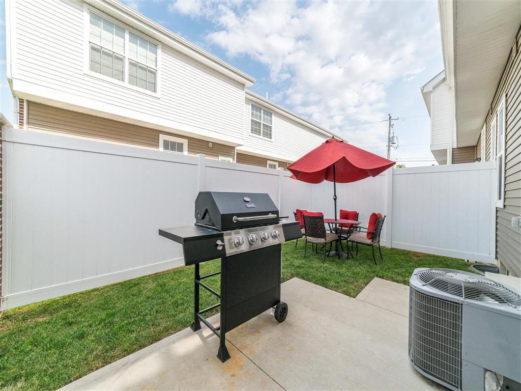 a backyard with a grill and a table with a red umbrella