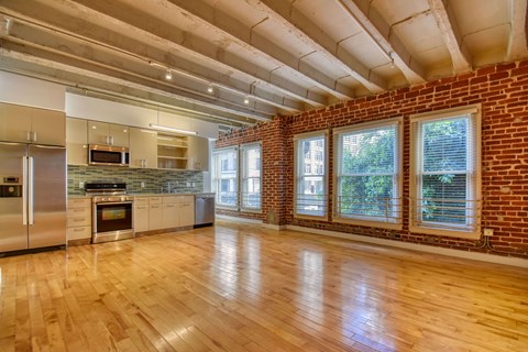 A kitchen with wooden floors and a brick wall.