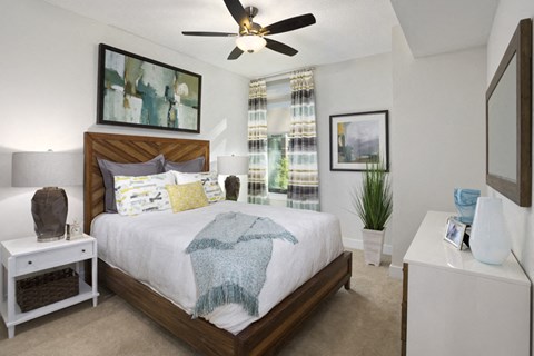A bedroom with a bed, nightstand, and a ceiling fan.