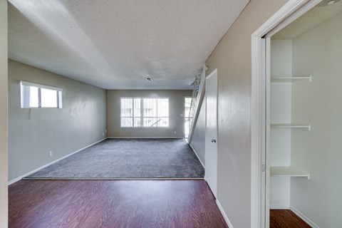 the living room of an apartment with wood flooring and white walls