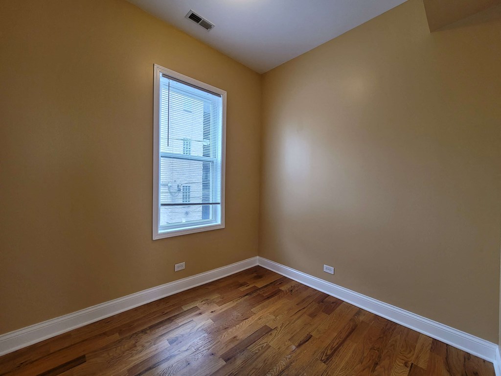 an empty room with wooden floors and a window