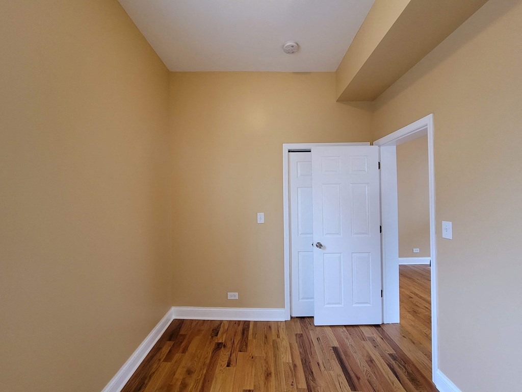 a bedroom with a white door and wooden floors