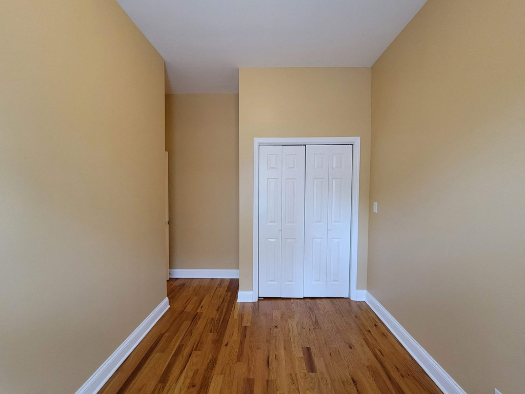 a empty room with a white door and wood floors