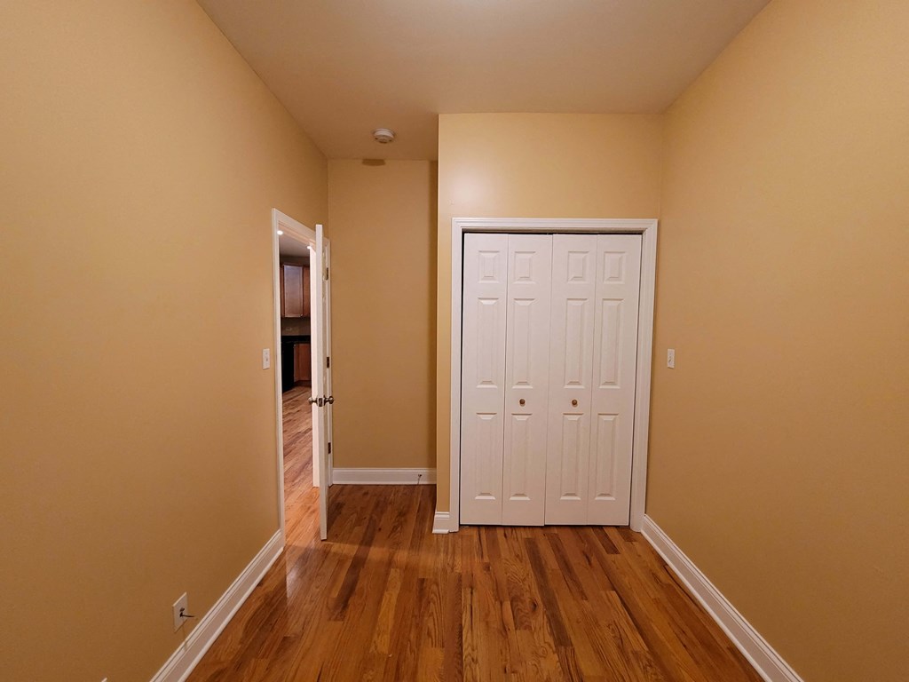a bedroom with a white door and wooden floors
