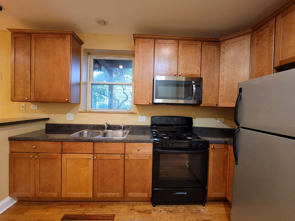 a kitchen with wooden cabinets and a black stove and refrigerator