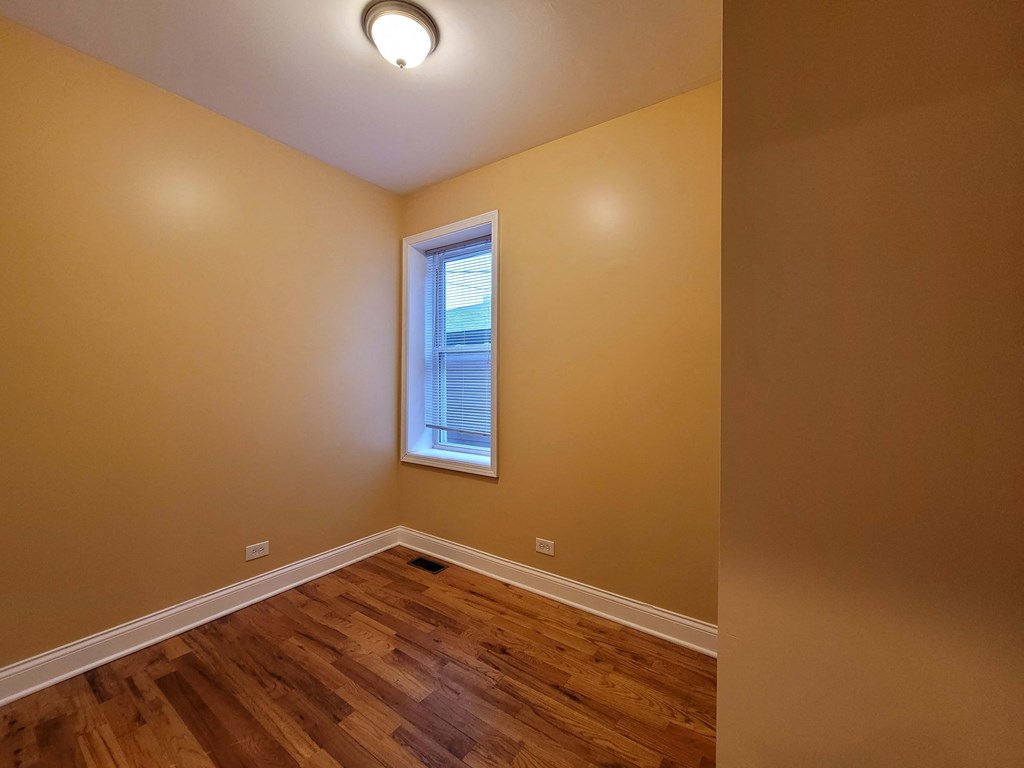 a empty room with a window and wooden floors