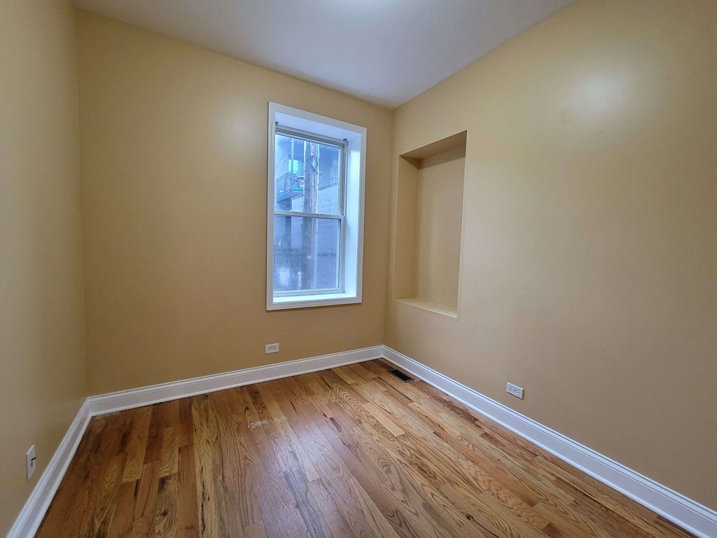 a bedroom with wood flooring and a window