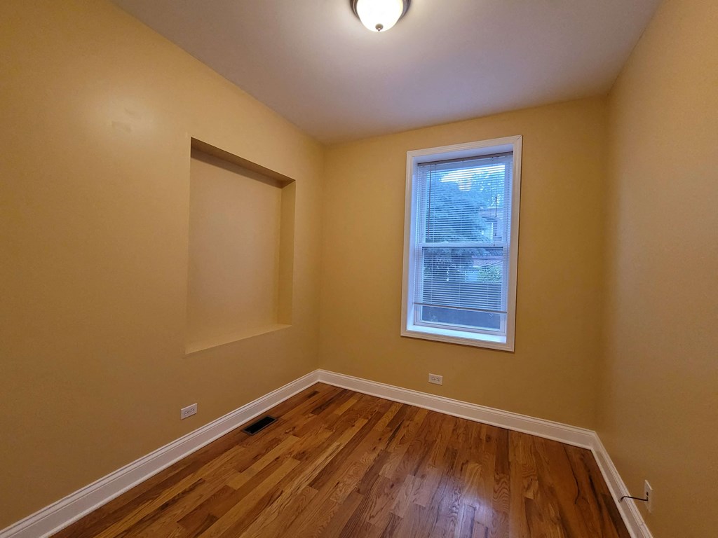 a empty room with a window and wooden floors