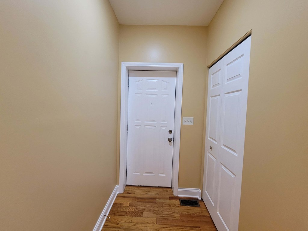 a hallway with a white door and a door to a closet