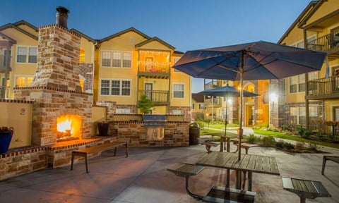 a patio with picnic tables and a fireplace at night
