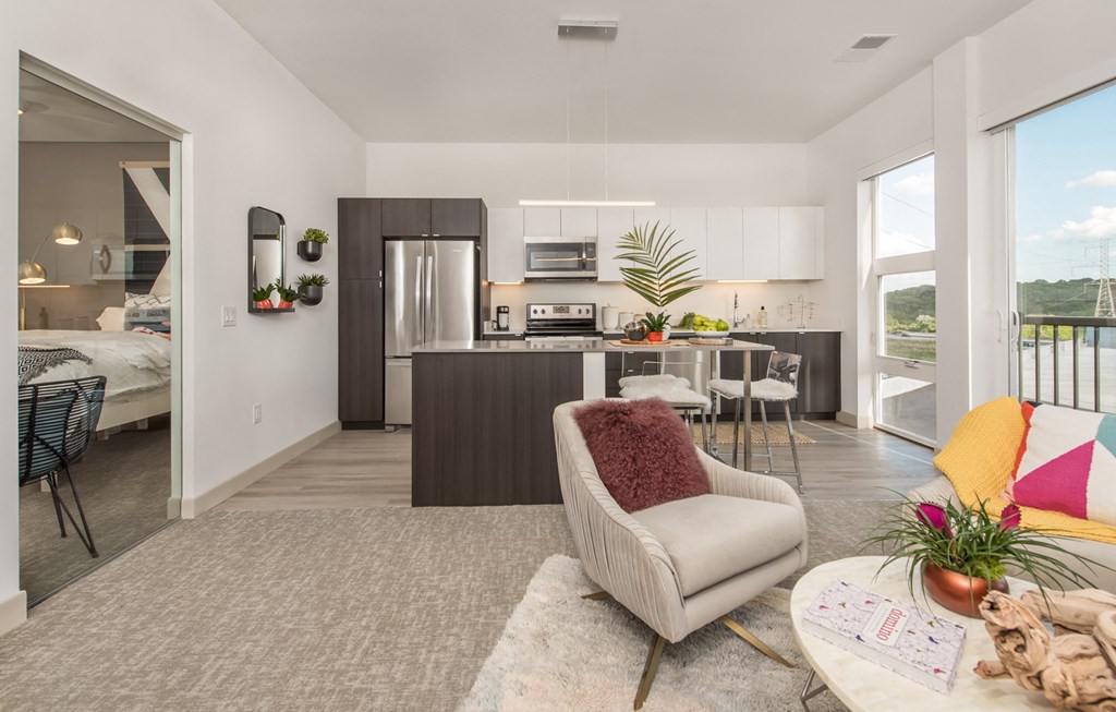 a living room with a couch and a chair in front of a kitchen