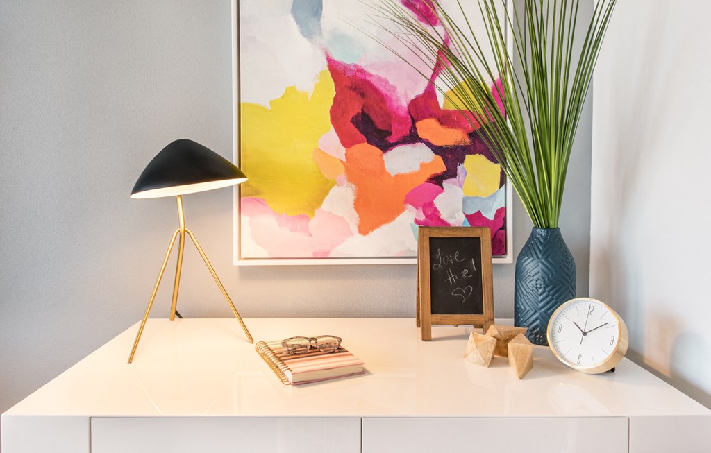 a desk with a clock and a vase with a plant on it