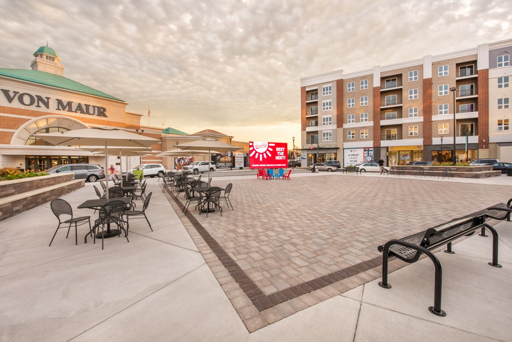 an empty parking lot with tables and chairs in front of an apartment building