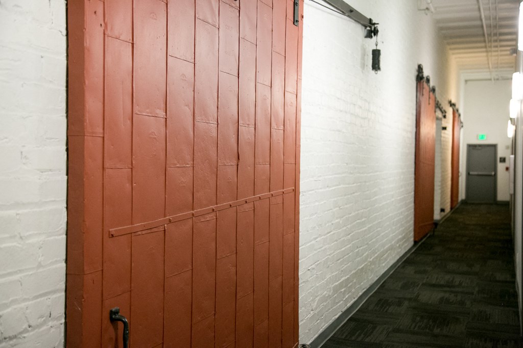 red warehouse doors and white walls in fix play hallway at Fix Play Lofts, Birmingham, AL, 35203